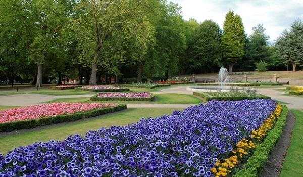 Beds of brightly coloured flowers with a fountain in the background