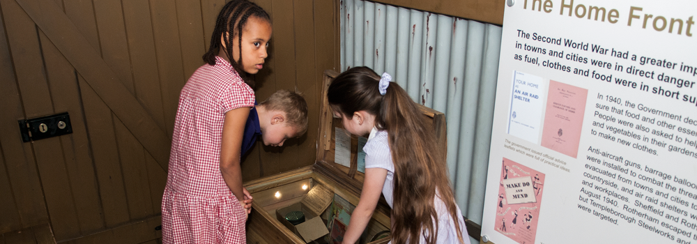 Three schoolchildren looking at objects on display