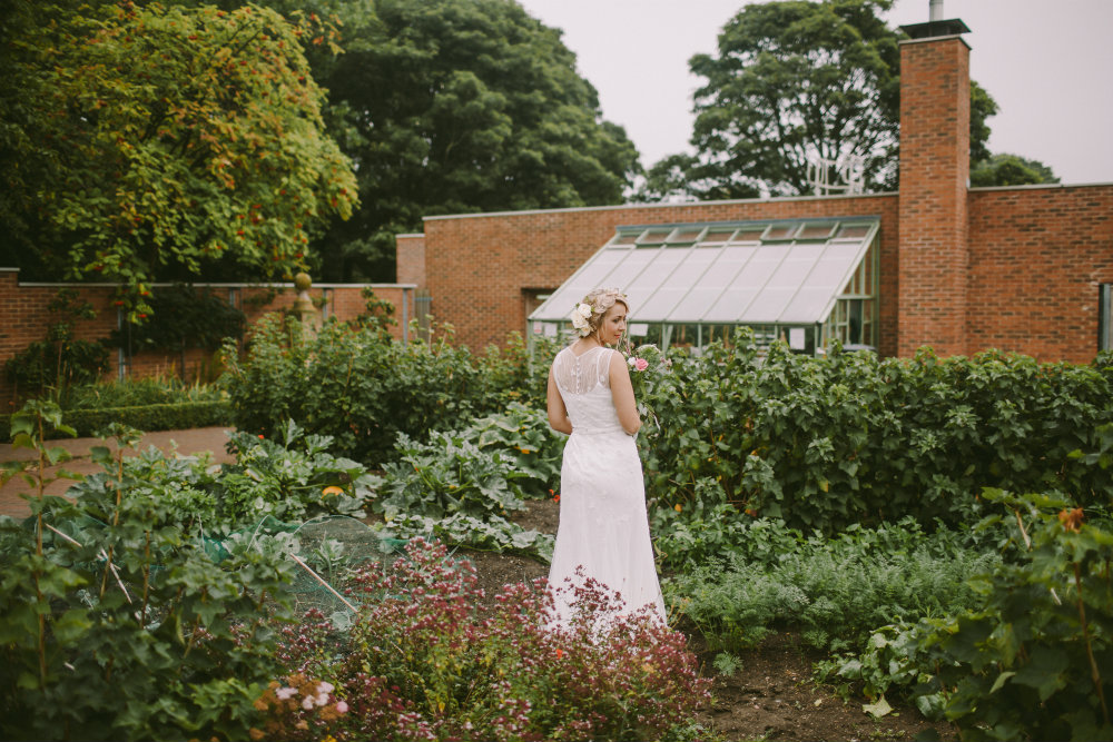 Bride stood amongst plants and flowers in the Garden House garden.
