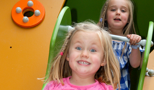 Two girls playing on a slide in the play park.